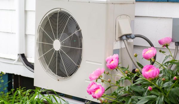 heat pump next to flowers in a garden outside of a home
